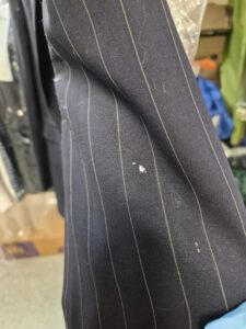 Close-up of a dark pinstripe fabric with a small white stain or spot visible near the center.